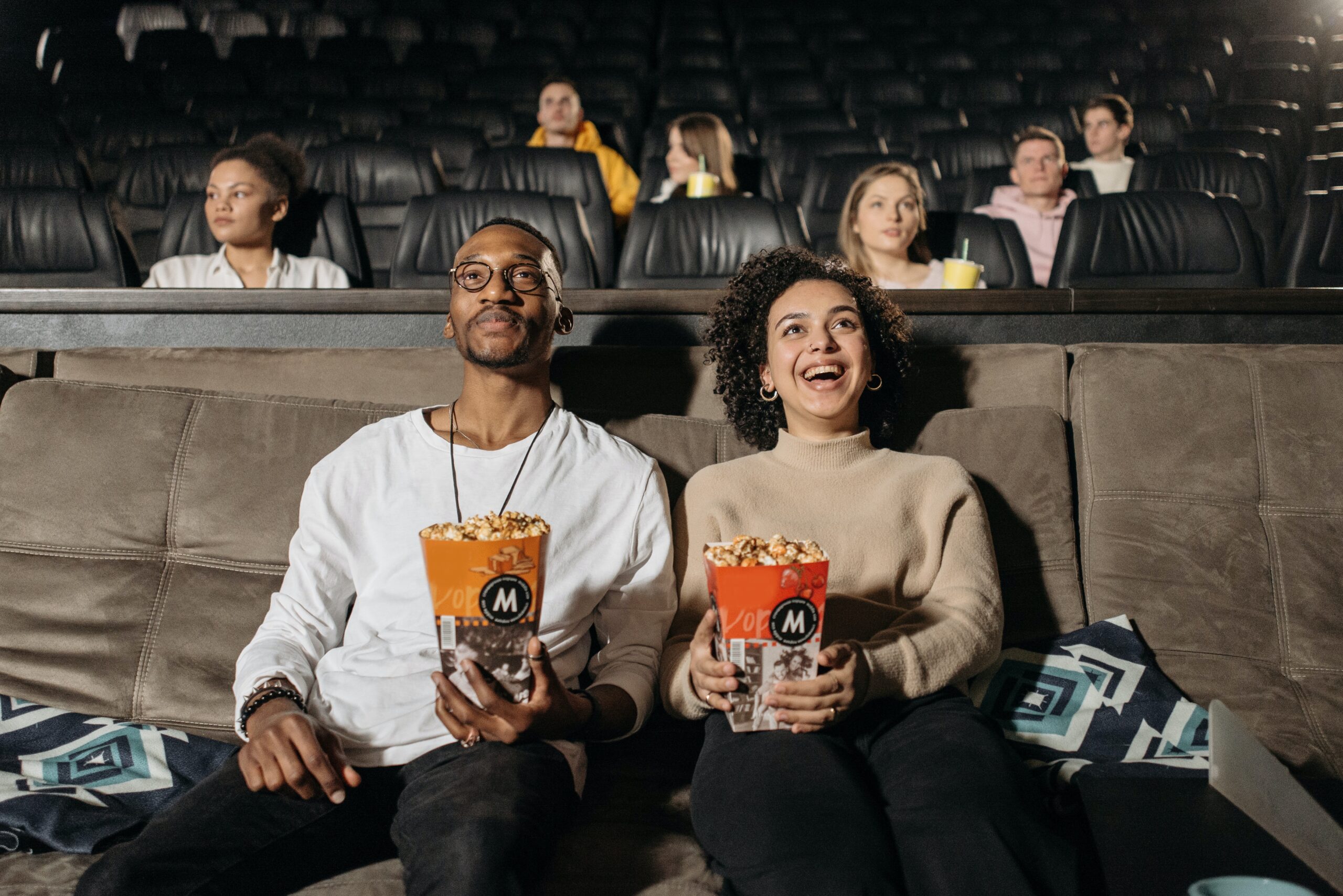 Couple holding popcorn looking up at cinema screen off camera